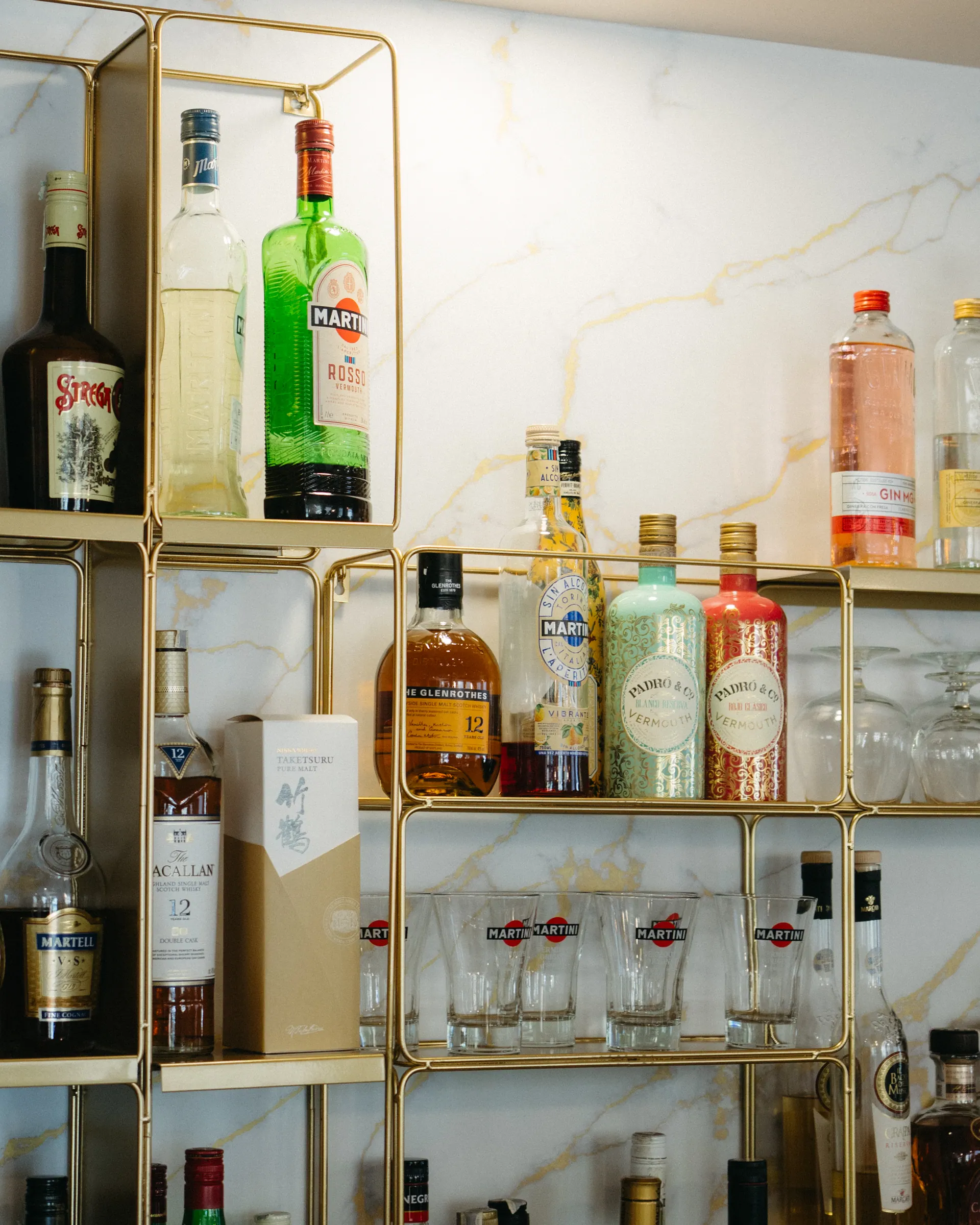 La barra de GIÀ: estantería de latón sobre mármol con vinos, vermut y destilados italianos