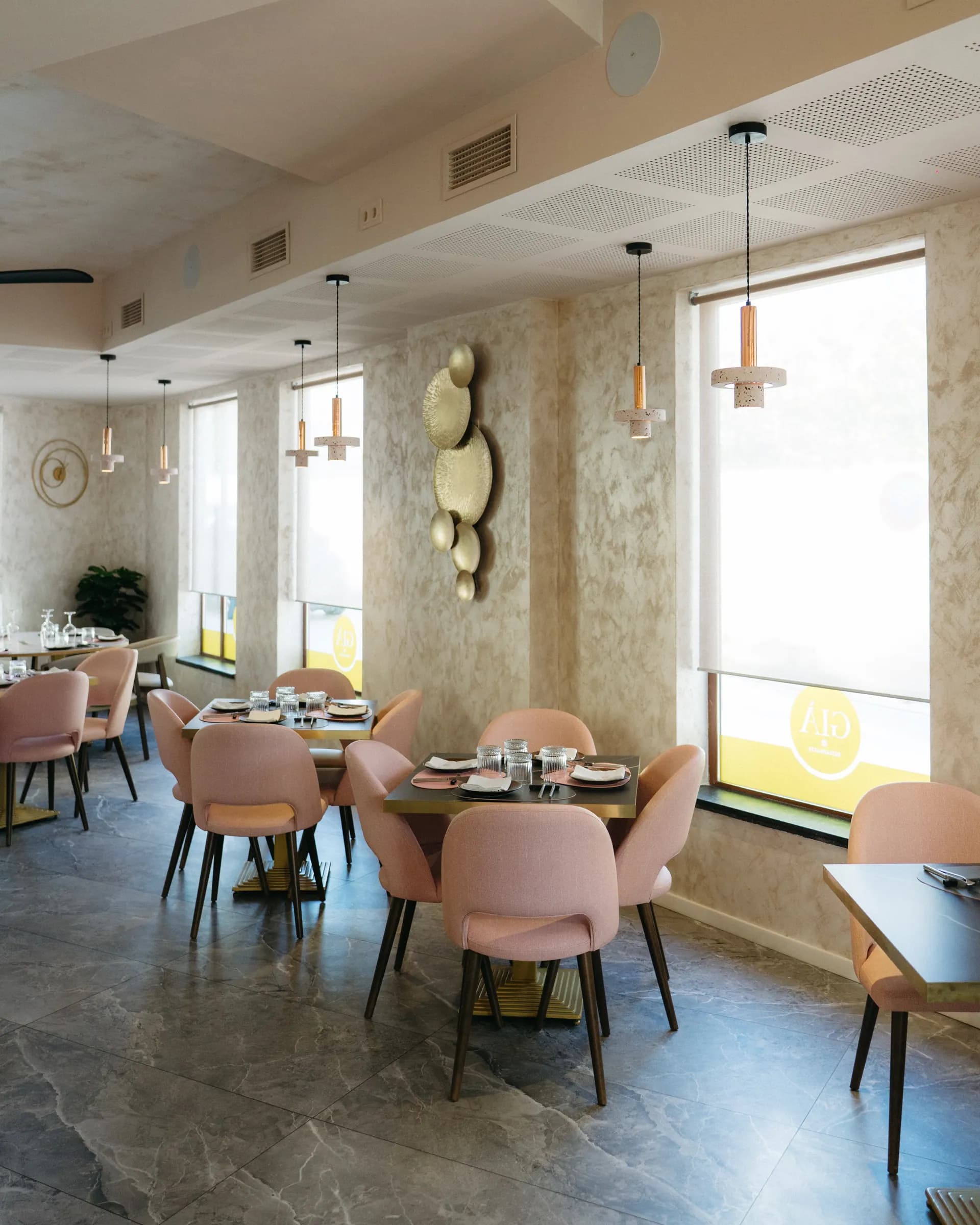 Sala interior del Restaurante Già — sillas rosa palo, paredes estuco, lámparas cobre